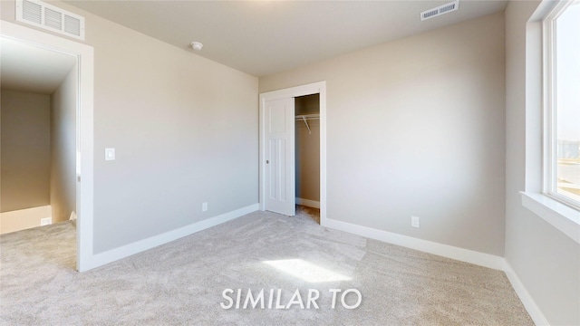 unfurnished bedroom featuring a closet and light carpet