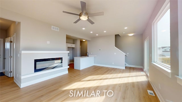 unfurnished living room featuring ceiling fan and light wood-type flooring