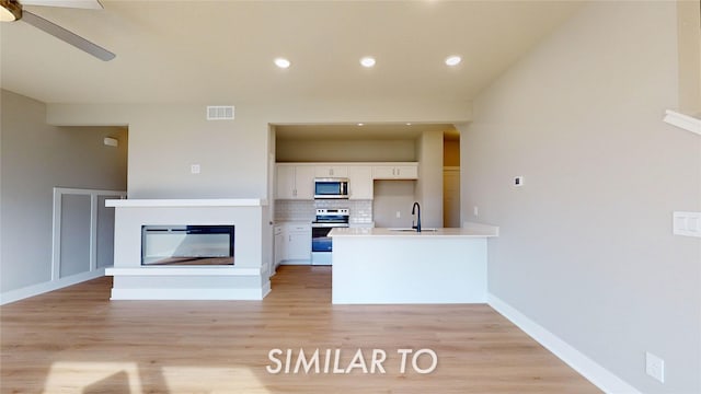 kitchen featuring stainless steel appliances, sink, white cabinetry, ceiling fan, and backsplash