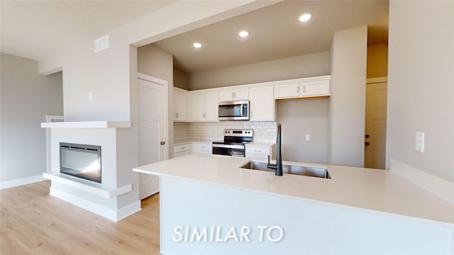 kitchen featuring kitchen peninsula, stainless steel appliances, backsplash, white cabinetry, and sink