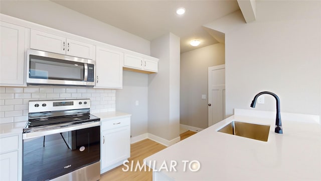 kitchen featuring appliances with stainless steel finishes, tasteful backsplash, white cabinets, and sink