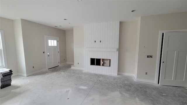unfurnished living room with baseboards and a fireplace