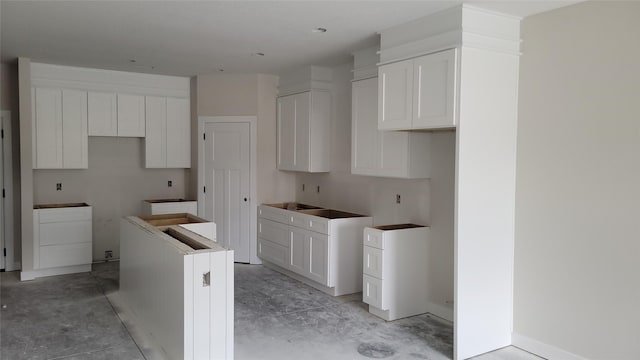 kitchen with concrete floors, white cabinetry, and a kitchen island