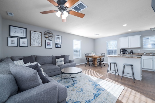 living room with hardwood / wood-style flooring, ceiling fan, and sink