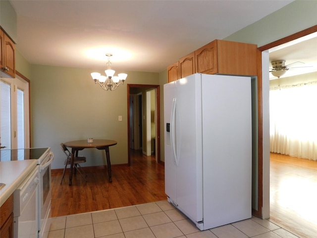 kitchen featuring white appliances, light tile patterned floors, pendant lighting, and ceiling fan with notable chandelier