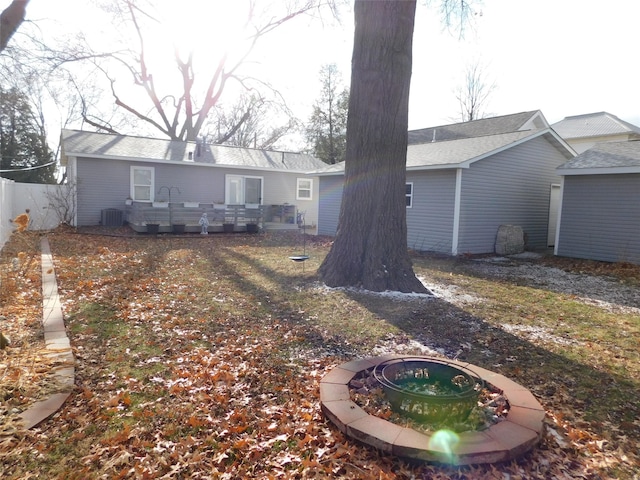 rear view of property featuring an outdoor fire pit and central air condition unit