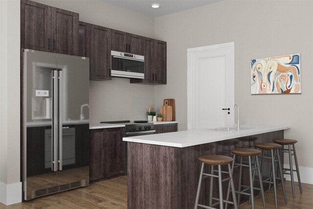 kitchen featuring dark hardwood / wood-style flooring, a kitchen bar, high quality fridge, sink, and dark brown cabinets