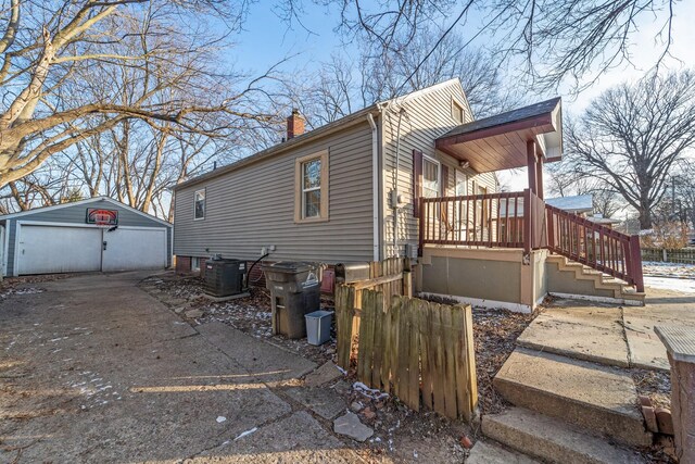 view of home's exterior with a garage, central AC, and an outbuilding