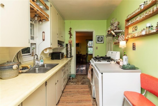 kitchen with white cabinetry, sink, and white gas range oven