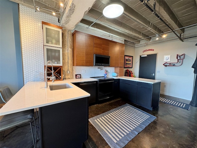 kitchen featuring sink, a kitchen bar, kitchen peninsula, backsplash, and black appliances