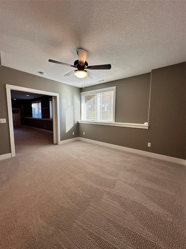 carpeted empty room featuring ceiling fan and a textured ceiling