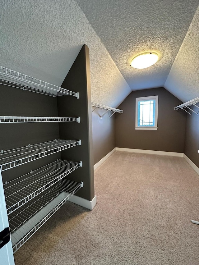 walk in closet with vaulted ceiling and carpet flooring