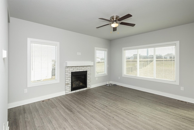 unfurnished living room with a brick fireplace, ceiling fan, and hardwood / wood-style flooring