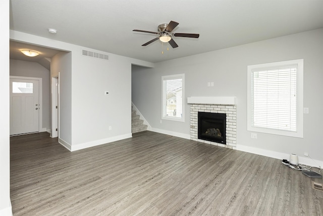 unfurnished living room with a brick fireplace, ceiling fan, and hardwood / wood-style flooring