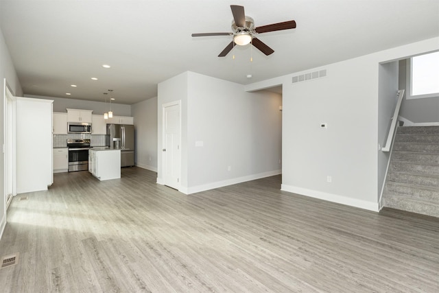 unfurnished living room featuring ceiling fan and light hardwood / wood-style floors