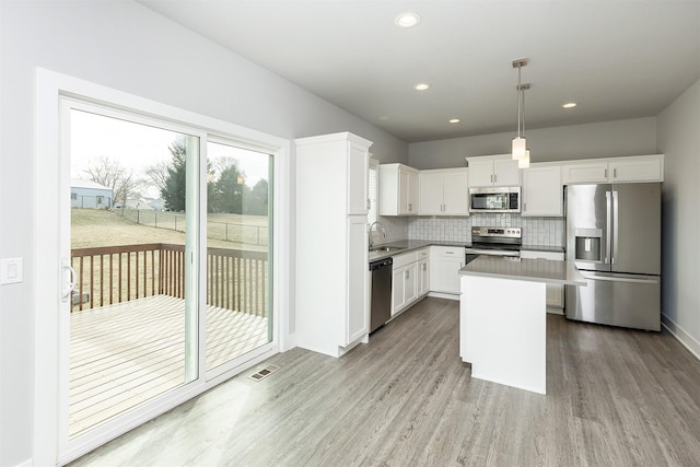 kitchen featuring light hardwood / wood-style flooring, a center island, decorative light fixtures, stainless steel appliances, and white cabinets