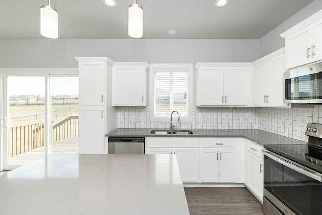 kitchen featuring decorative light fixtures, appliances with stainless steel finishes, white cabinetry, and sink