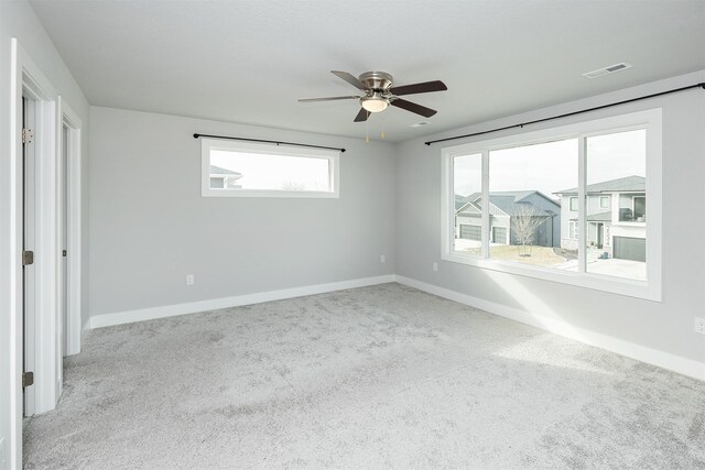 carpeted empty room featuring ceiling fan and plenty of natural light