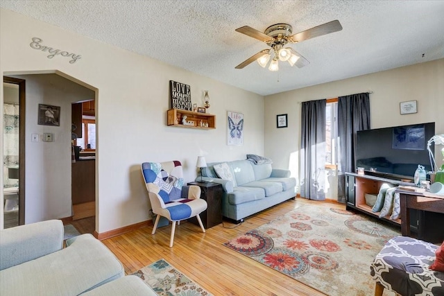 living room featuring wood-type flooring, a textured ceiling, and ceiling fan