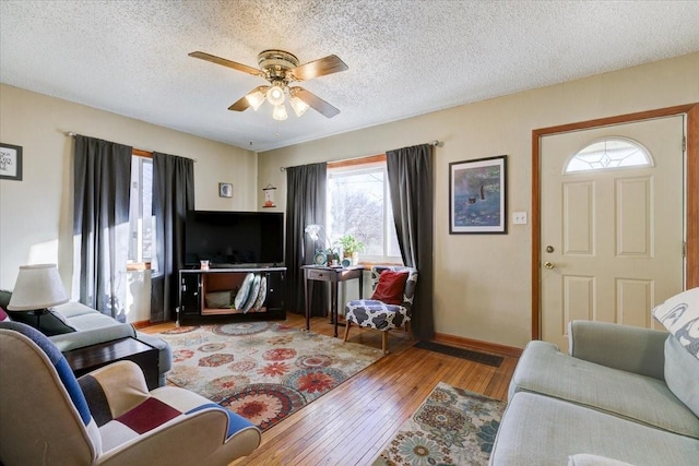 living room featuring a textured ceiling, ceiling fan, and light wood-type flooring