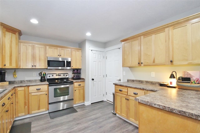 kitchen with stainless steel appliances, light brown cabinets, and light hardwood / wood-style floors