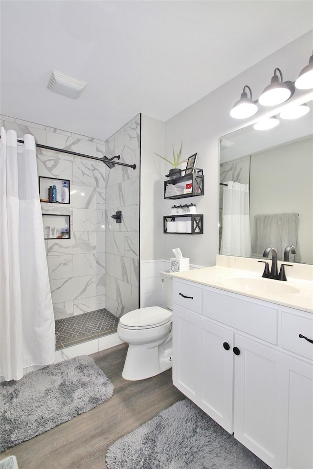 bathroom featuring toilet, hardwood / wood-style flooring, walk in shower, and vanity