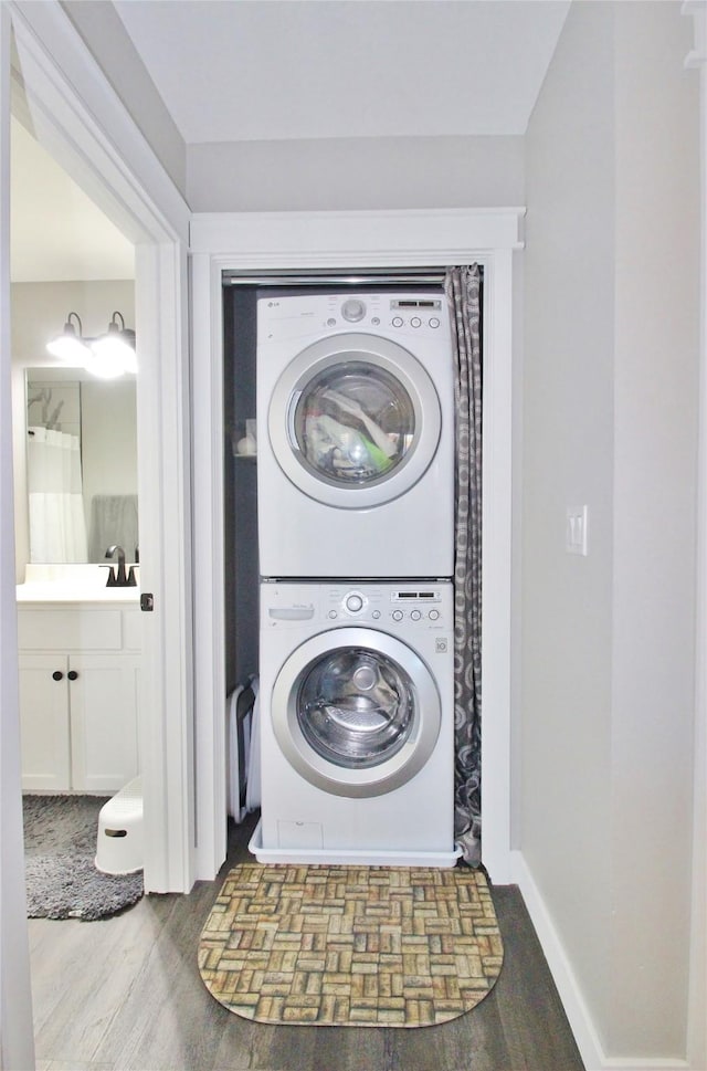 laundry area featuring stacked washer and dryer and hardwood / wood-style floors