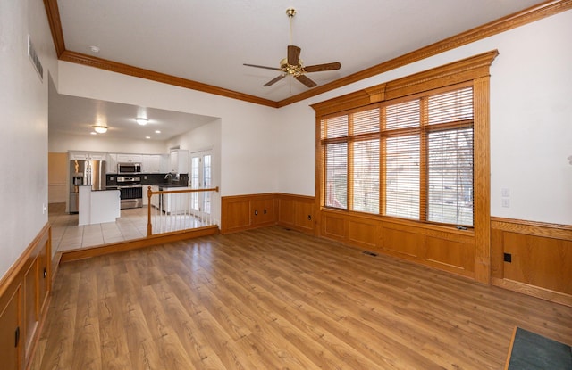 unfurnished living room featuring crown molding, light hardwood / wood-style floors, and ceiling fan