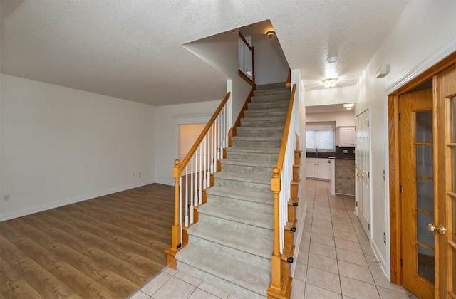 stairway with sink, tile patterned floors, and a textured ceiling