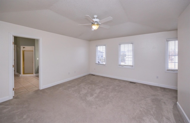 carpeted spare room with ceiling fan and vaulted ceiling