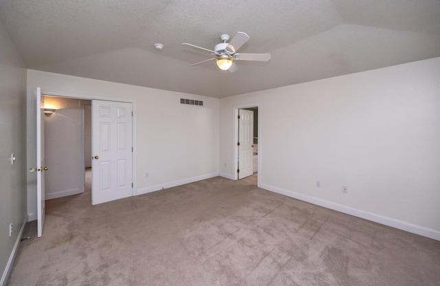 unfurnished bedroom featuring light colored carpet, vaulted ceiling, and a textured ceiling