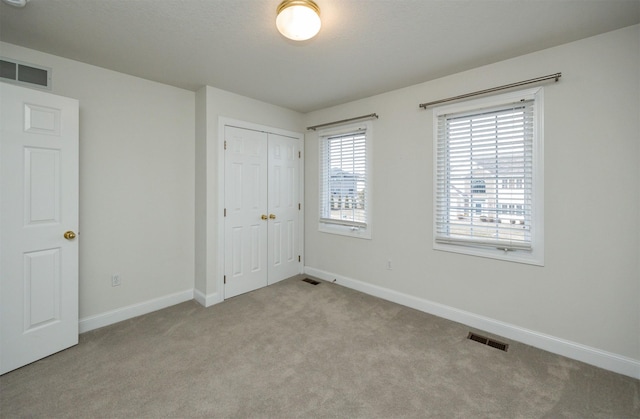 unfurnished bedroom featuring light colored carpet and a closet