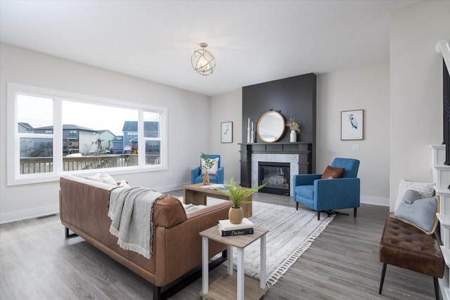 living room with a tiled fireplace and wood-type flooring