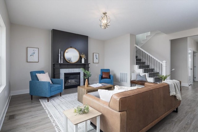 living room featuring a tiled fireplace, a chandelier, and hardwood / wood-style flooring