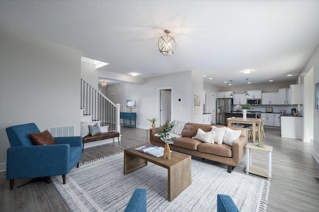 living room with an inviting chandelier and light hardwood / wood-style flooring