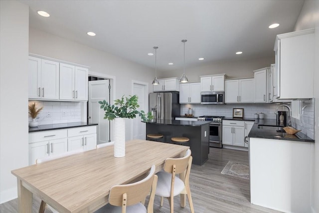 kitchen with sink, white cabinets, a center island, hanging light fixtures, and appliances with stainless steel finishes