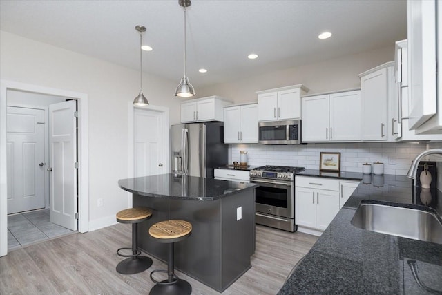 kitchen with stainless steel appliances, sink, decorative light fixtures, white cabinetry, and decorative backsplash