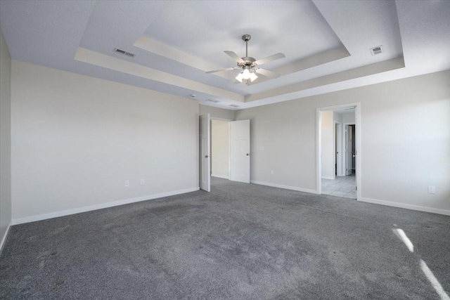 empty room featuring carpet flooring, ceiling fan, and a tray ceiling