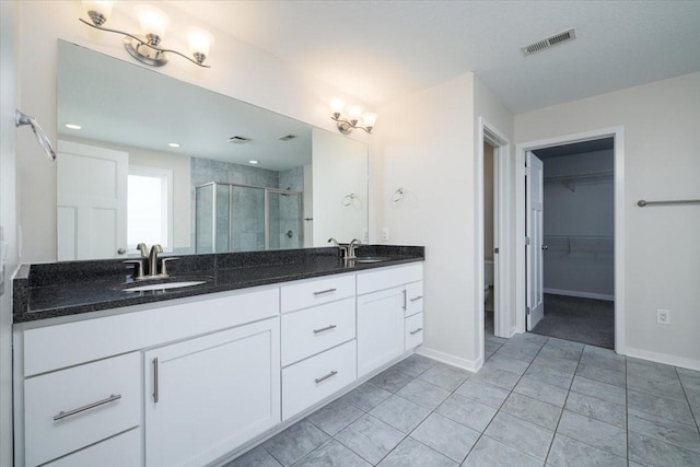 bathroom featuring an inviting chandelier, a shower with shower door, and vanity