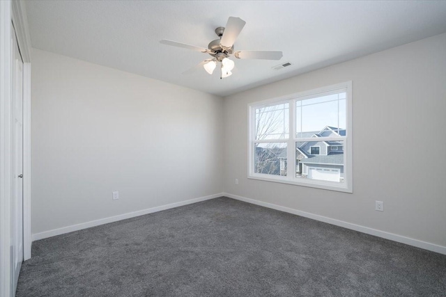 spare room with ceiling fan and dark carpet