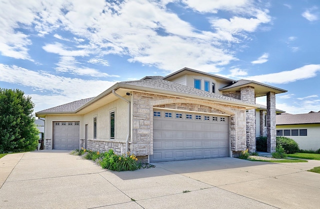 view of front of home featuring a garage, stone siding, a shingled roof, and driveway