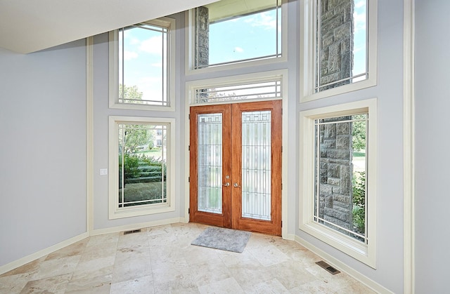 foyer featuring a towering ceiling, french doors, and a healthy amount of sunlight