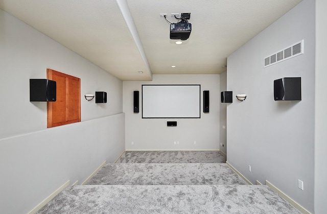 cinema with a textured ceiling, light carpet, visible vents, and baseboards