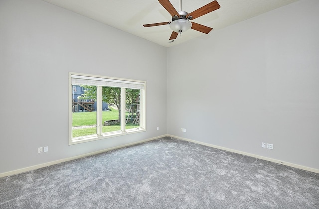 carpeted spare room featuring baseboards, vaulted ceiling, and a ceiling fan