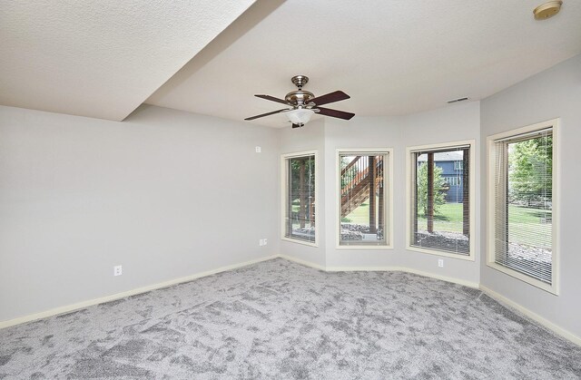 carpeted spare room with a textured ceiling and ceiling fan