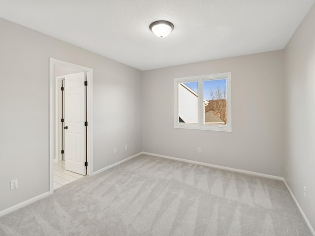 unfurnished room featuring a textured ceiling and light carpet