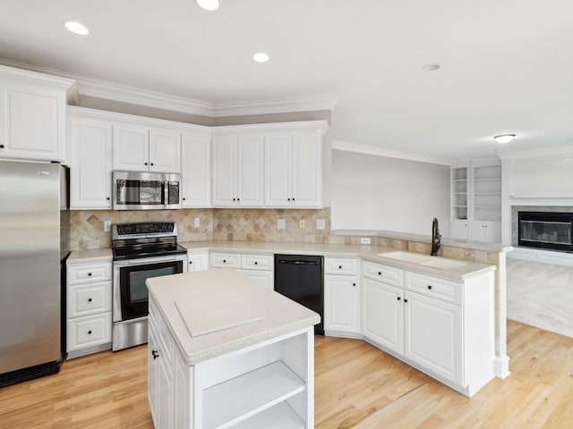 kitchen with sink, white cabinetry, ornamental molding, a kitchen island, and appliances with stainless steel finishes