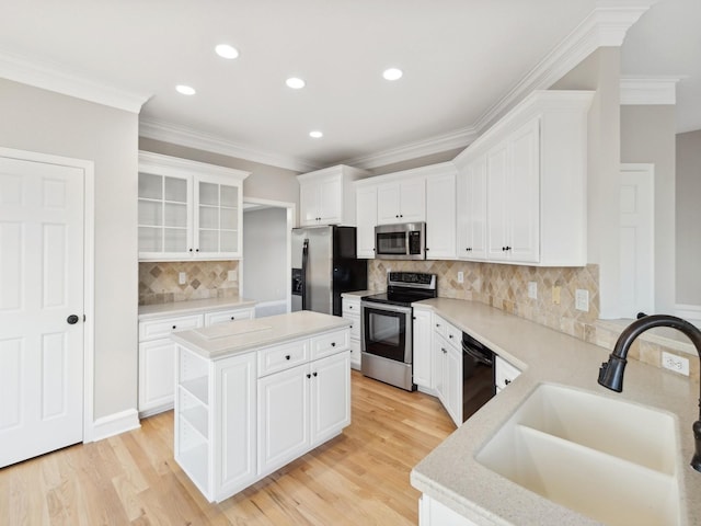 kitchen with a kitchen island, backsplash, white cabinets, appliances with stainless steel finishes, and sink