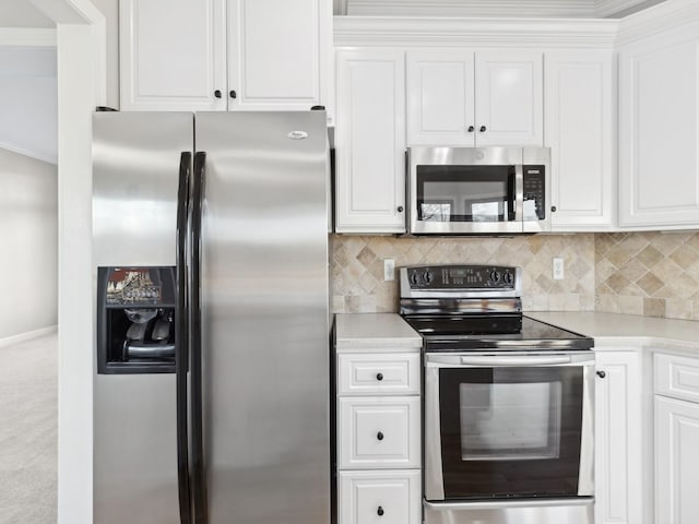 kitchen featuring white cabinets, stainless steel appliances, backsplash, and crown molding