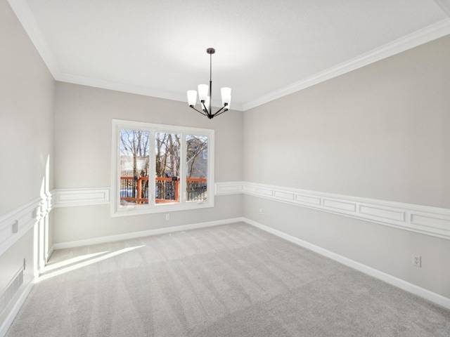 spare room with crown molding, a chandelier, and carpet